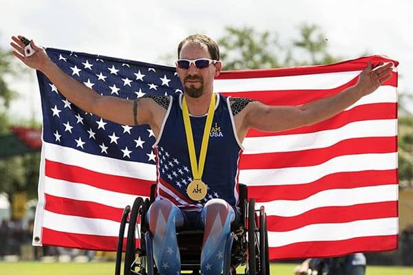 Man in wheelchair holding American flag with medal