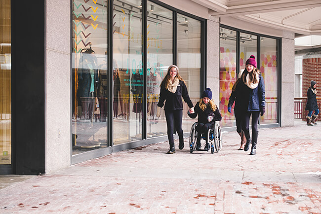 teenage girl sitting on a wheelchair out on winter Christmas shopping with her friends