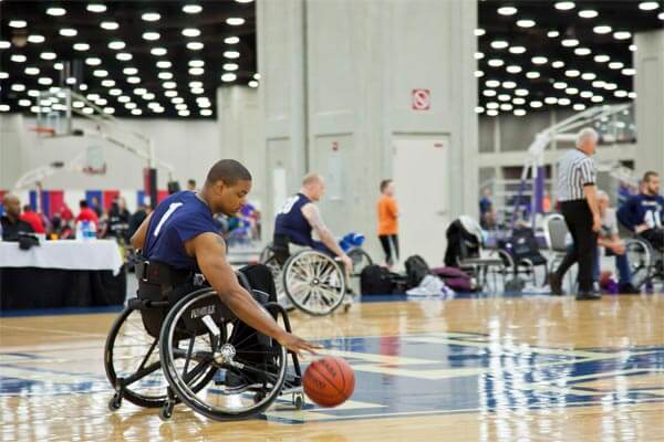man in wheelchair playing basketball at indoor court