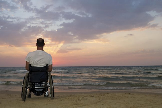 man sitting in a wheelchair patiently waiting for a sunrise