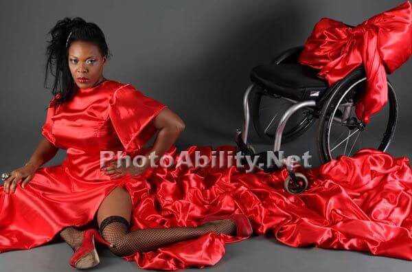 image of a lady posing elegantly in a red dress with her wheelchair beside her