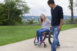 image of a woman sitting on a wheelchair holding hands with her boyfriend walking beside her
