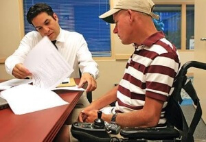 Two men at a boardroom table reviewing papers one man is in a wheelchair 300x207 - Disabled starting Business