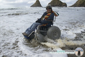 a disabled woman sitting on a beach wheelchair at beach and smiling