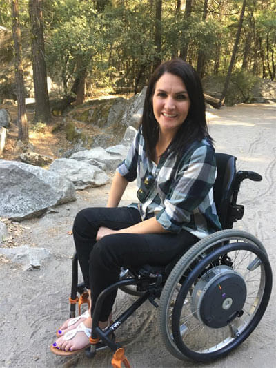 image of a woman sitting on a wheelchair on road and smiling