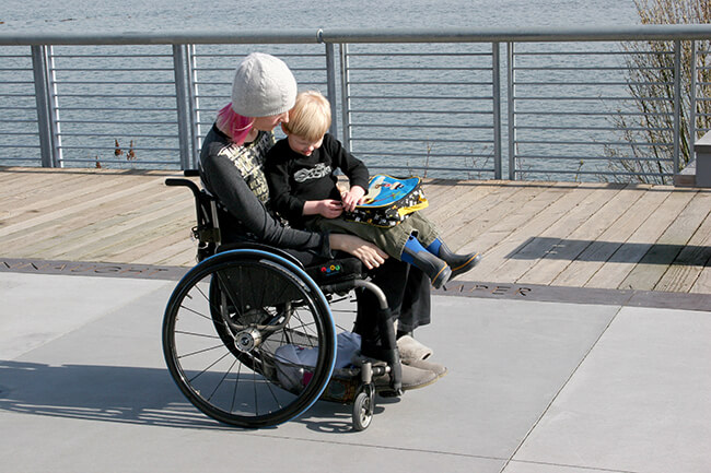 image of a disabled woman on a wheelchair with her son sitting on her lap