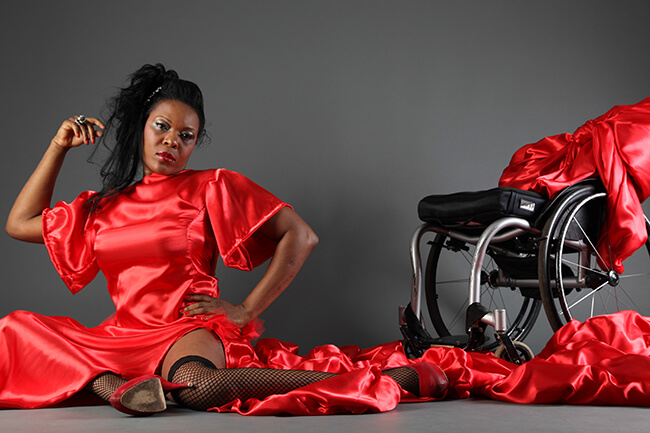 A women in a red dress sitting beside a wheelchair