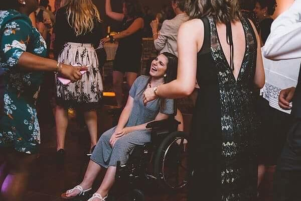 Women in a wheelchair on the dance floor laughing along with the crowd