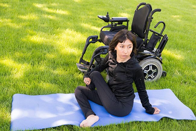 Reveca Torres founder of back bones online doing a yoga pose in grass