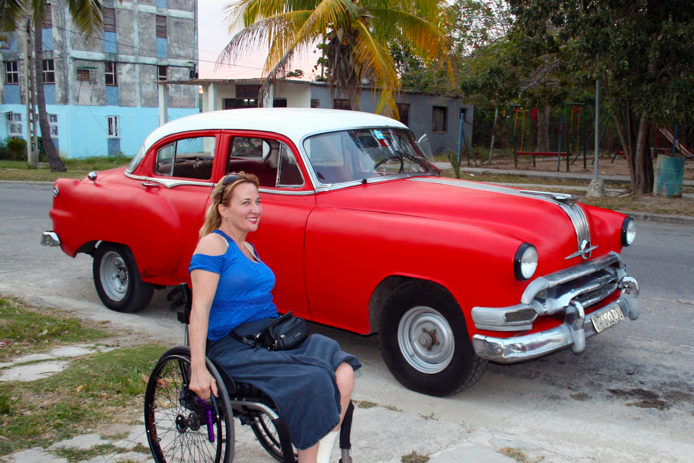 Woman using wheelchair in a Cuban street with a classic car - Wheelchair Travel: Cuba Libre? How Free is Cuba for Travelers on Wheels?